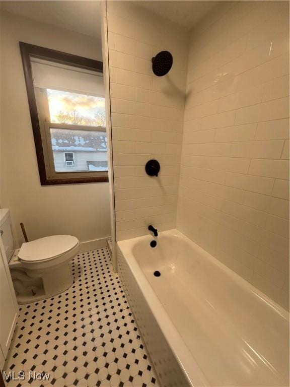 bathroom featuring tile patterned flooring, toilet, and tiled shower / bath