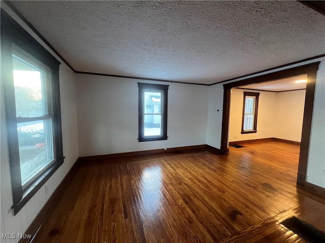 spare room featuring crown molding, hardwood / wood-style floors, and a textured ceiling