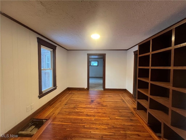 spare room featuring crown molding, hardwood / wood-style floors, and a textured ceiling