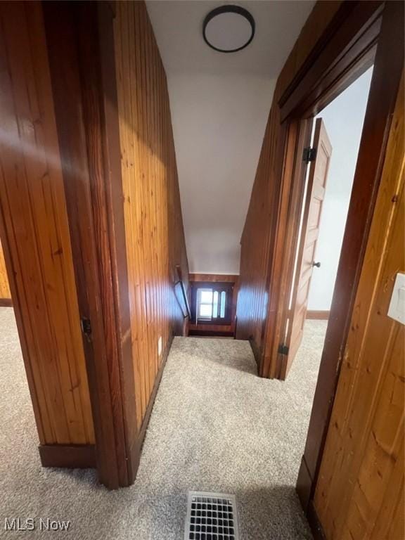 corridor featuring carpet floors and wooden walls