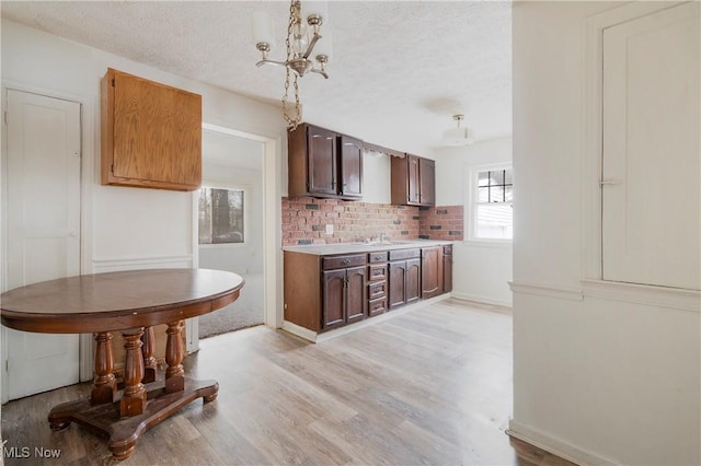 kitchen featuring dark brown cabinetry, light hardwood / wood-style flooring, a textured ceiling, and a notable chandelier