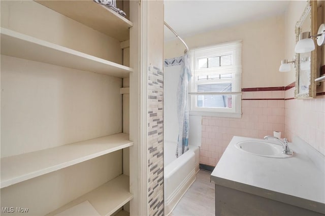 bathroom featuring vanity, shower / bath combo with shower curtain, and tile walls