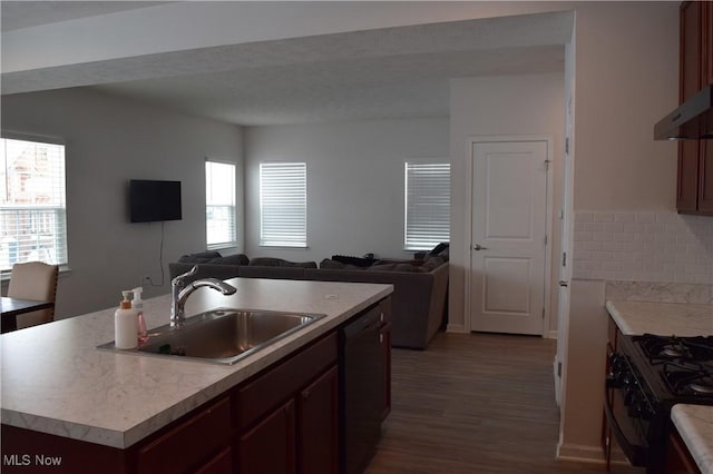 kitchen with sink, an island with sink, black appliances, and plenty of natural light