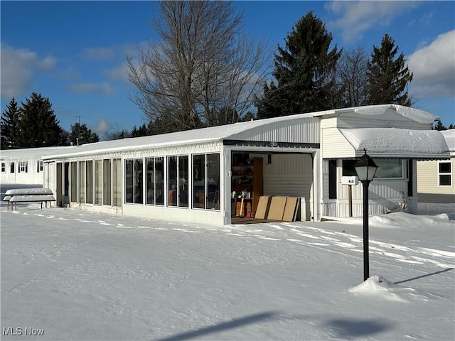 snow covered property with a sunroom