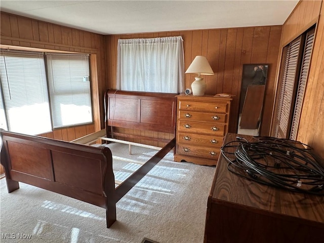 bedroom with a closet, wooden walls, and light carpet