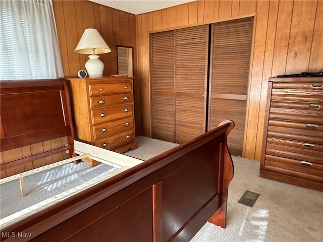 carpeted bedroom featuring wooden walls and a closet