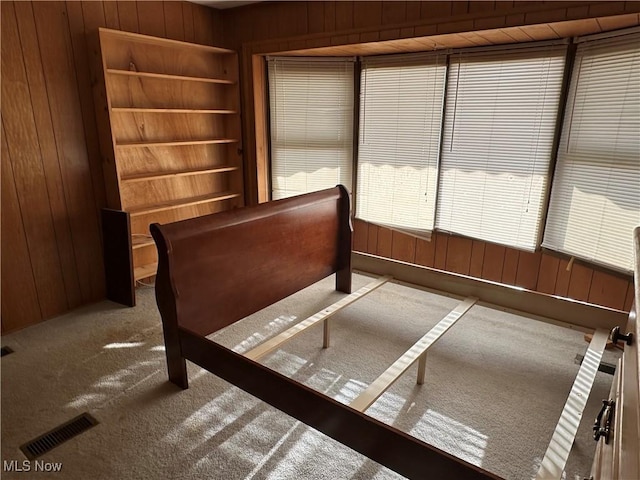 unfurnished bedroom with light colored carpet and wooden walls