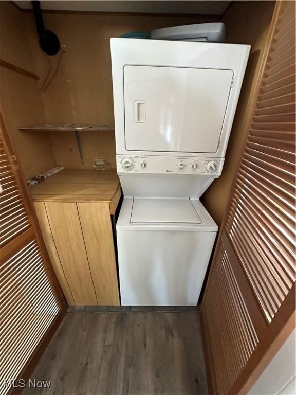 laundry room featuring dark hardwood / wood-style flooring and stacked washer / dryer