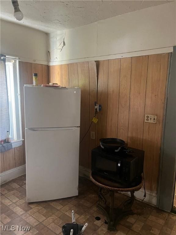 kitchen featuring white fridge and wooden walls