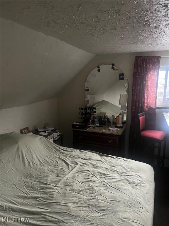 bedroom featuring lofted ceiling and a textured ceiling