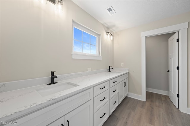 bathroom with hardwood / wood-style floors, vanity, and a textured ceiling