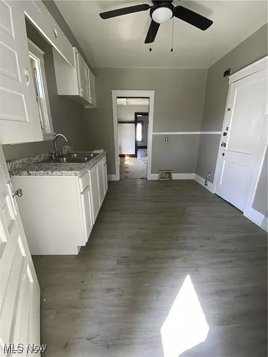 kitchen with dark wood-style floors, dark stone countertops, white cabinets, and a sink