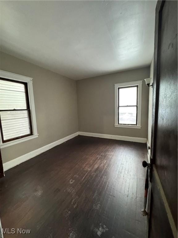 empty room featuring dark wood finished floors and baseboards