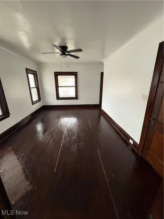 spare room with a ceiling fan, dark wood-style flooring, and baseboards