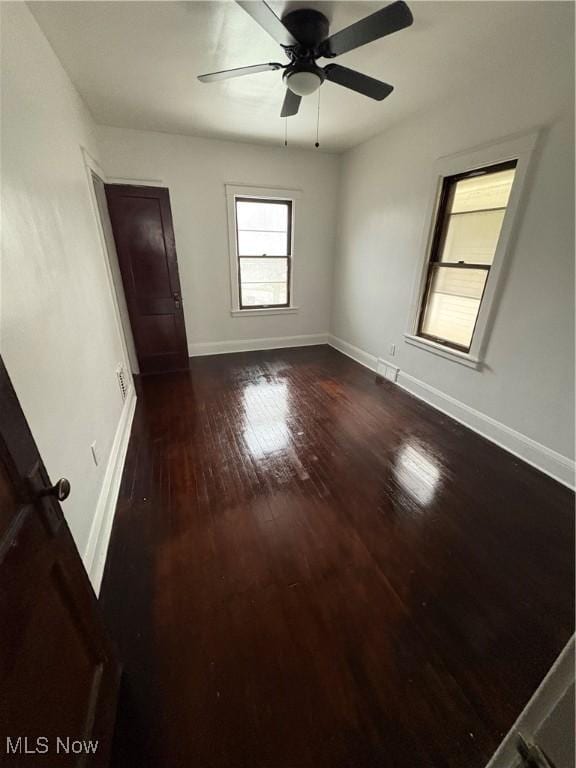 unfurnished bedroom featuring dark wood-type flooring, baseboards, and a ceiling fan