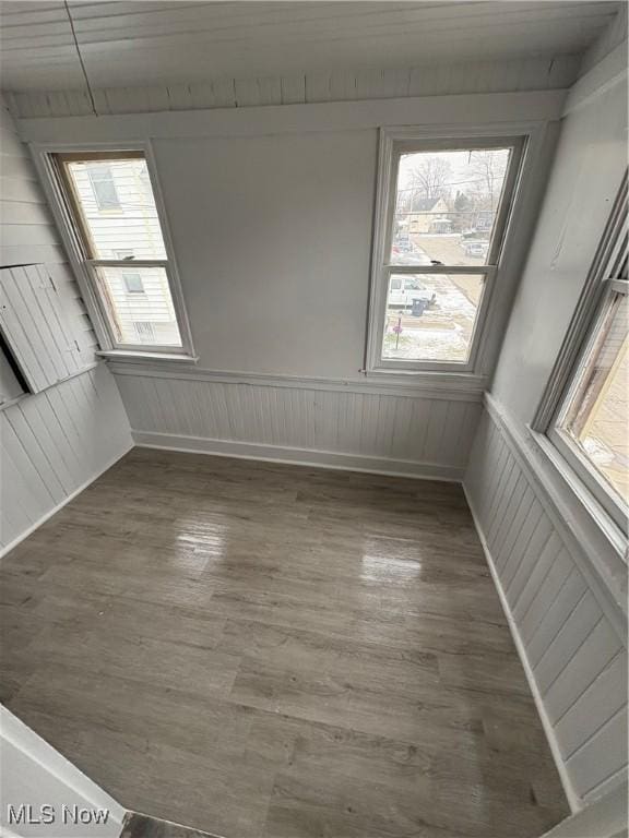 empty room featuring dark wood-style flooring and a wainscoted wall