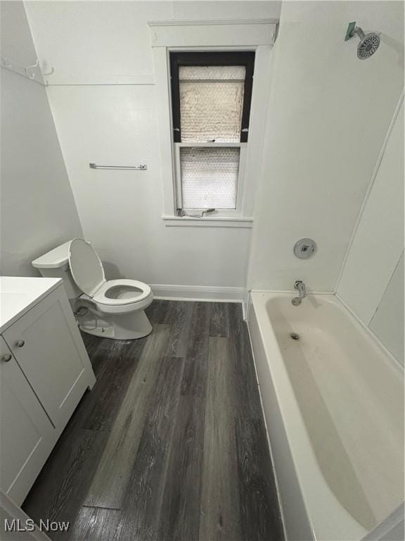 bathroom with toilet, wood finished floors, vanity, baseboards, and shower / bathing tub combination