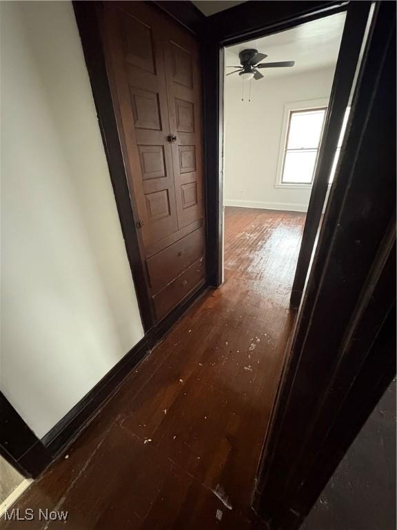 hallway featuring baseboards and wood finished floors