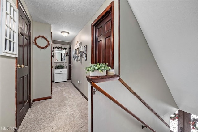 hall featuring light carpet and a textured ceiling