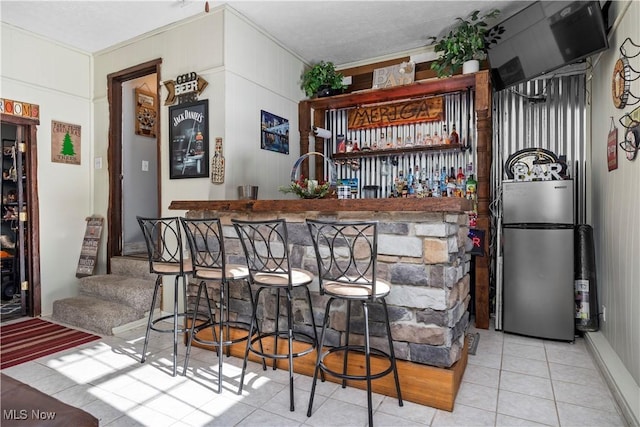 bar featuring stainless steel fridge and light tile patterned flooring