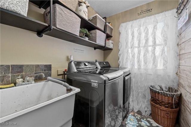 laundry room featuring washer and clothes dryer, a textured ceiling, and sink