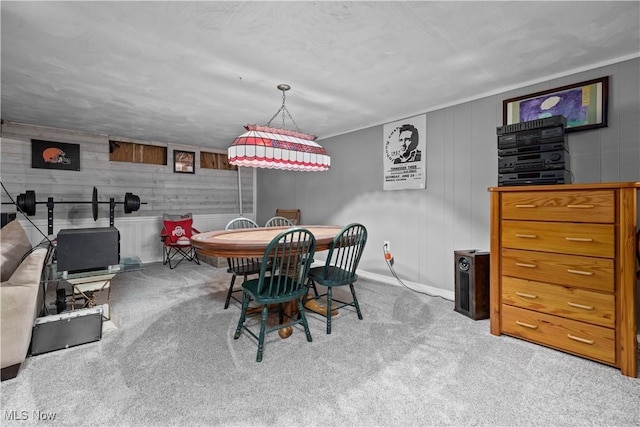 carpeted dining space with wooden walls and ornamental molding