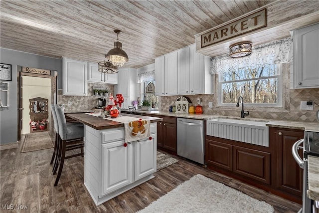 kitchen featuring butcher block counters, white cabinetry, sink, a kitchen island, and appliances with stainless steel finishes