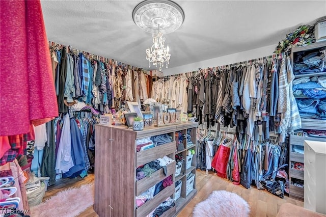 spacious closet featuring a chandelier and light hardwood / wood-style flooring