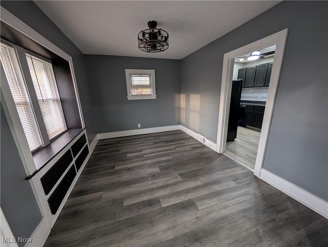 unfurnished dining area featuring dark wood-type flooring and a chandelier