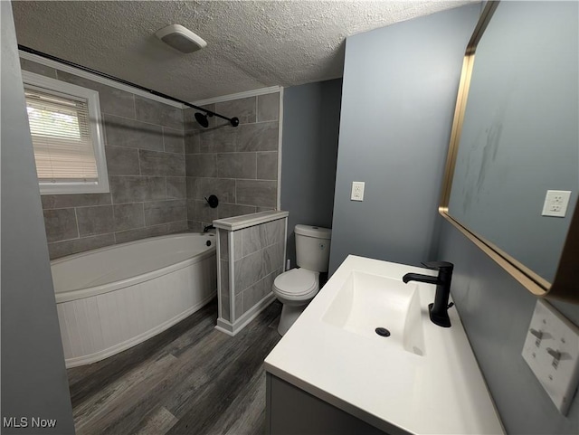 full bathroom featuring vanity, a textured ceiling, hardwood / wood-style flooring, toilet, and tiled shower / bath