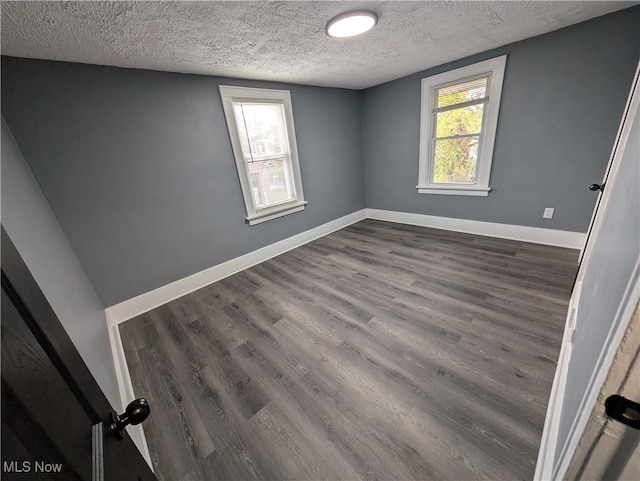 spare room featuring dark hardwood / wood-style flooring and a textured ceiling