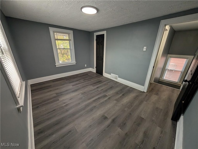 unfurnished room with a textured ceiling and dark hardwood / wood-style floors