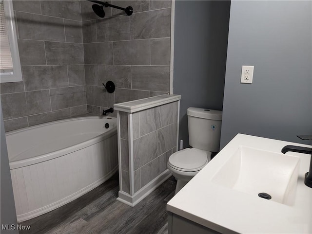 full bathroom featuring hardwood / wood-style floors, vanity, toilet, and tiled shower / bath