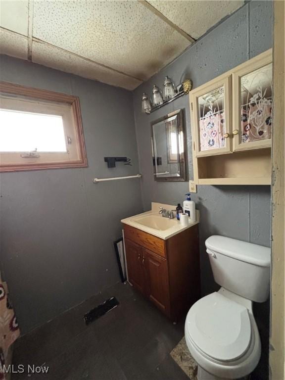 bathroom with a drop ceiling, toilet, and vanity