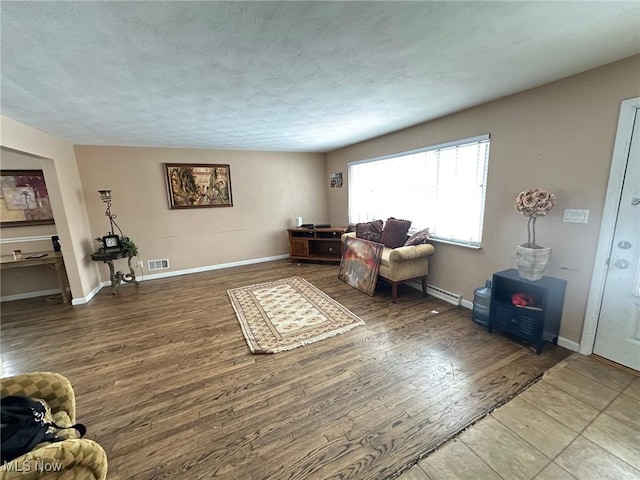 living room with a textured ceiling, hardwood / wood-style flooring, and a baseboard radiator