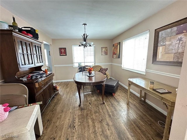 dining room featuring dark wood-type flooring, a healthy amount of sunlight, and a notable chandelier