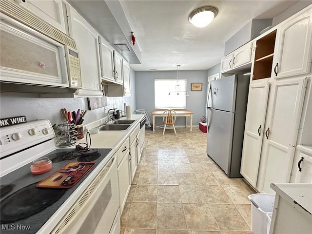 kitchen featuring sink, white cabinets, hanging light fixtures, and white appliances