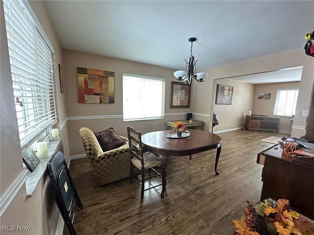 dining area featuring dark wood-type flooring and a chandelier