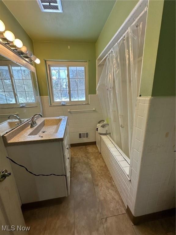 bathroom featuring vanity, tile walls, tile patterned floors, and shower / tub combo with curtain