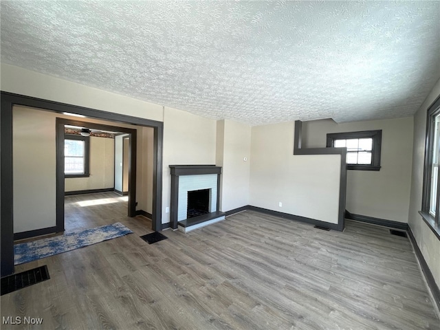 unfurnished living room featuring a fireplace, wood-type flooring, and a textured ceiling