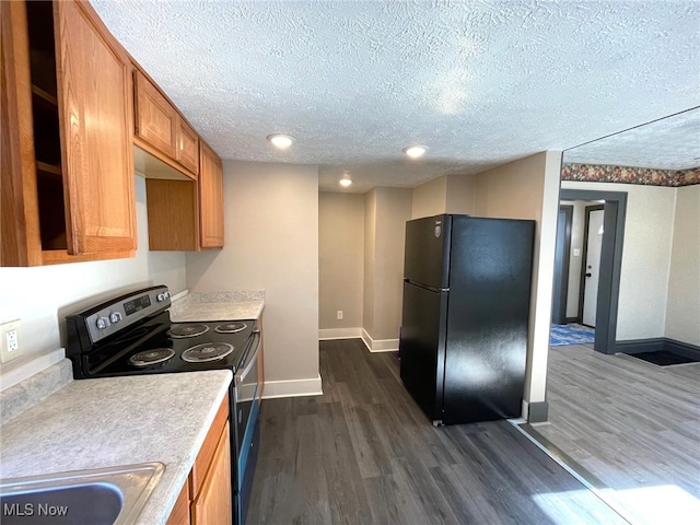 kitchen featuring black refrigerator, electric stove, sink, dark hardwood / wood-style floors, and a textured ceiling