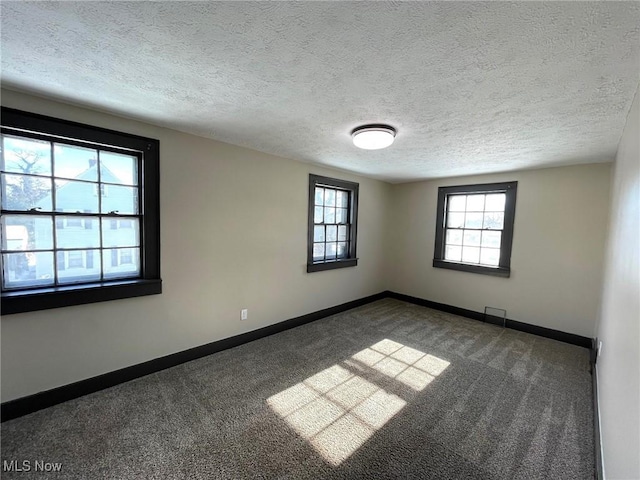 carpeted empty room featuring a textured ceiling