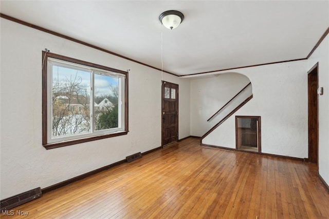 empty room with wood-type flooring and ornamental molding