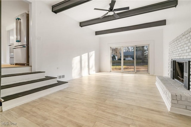 unfurnished living room with a fireplace, vaulted ceiling with beams, light hardwood / wood-style floors, and ceiling fan