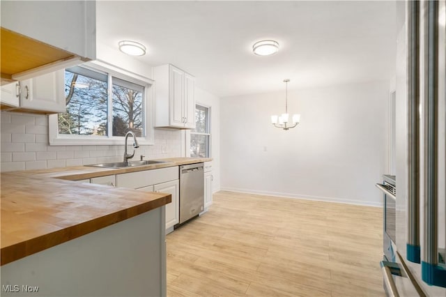 kitchen with wood counters, dishwasher, white cabinets, sink, and decorative light fixtures