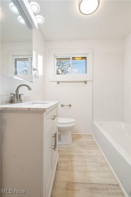 bathroom featuring a wealth of natural light, vanity, and toilet