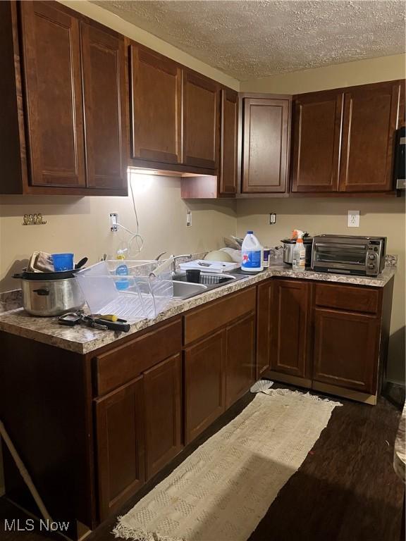 kitchen with dark hardwood / wood-style floors, sink, dark brown cabinets, and a textured ceiling