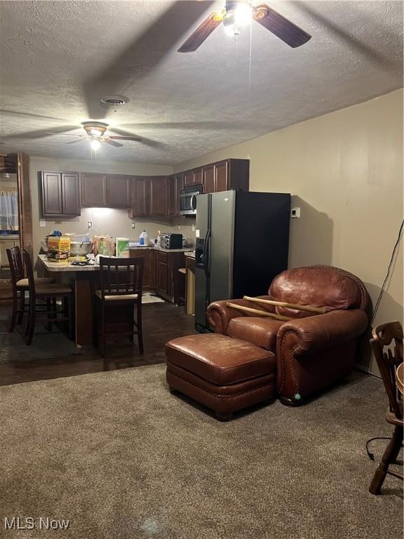 carpeted living room featuring ceiling fan and a textured ceiling