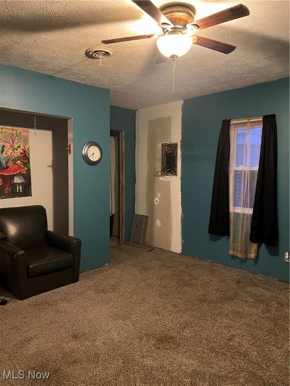 sitting room featuring carpet flooring, a textured ceiling, and ceiling fan