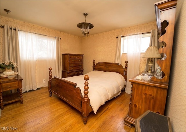 bedroom with light hardwood / wood-style floors and a chandelier